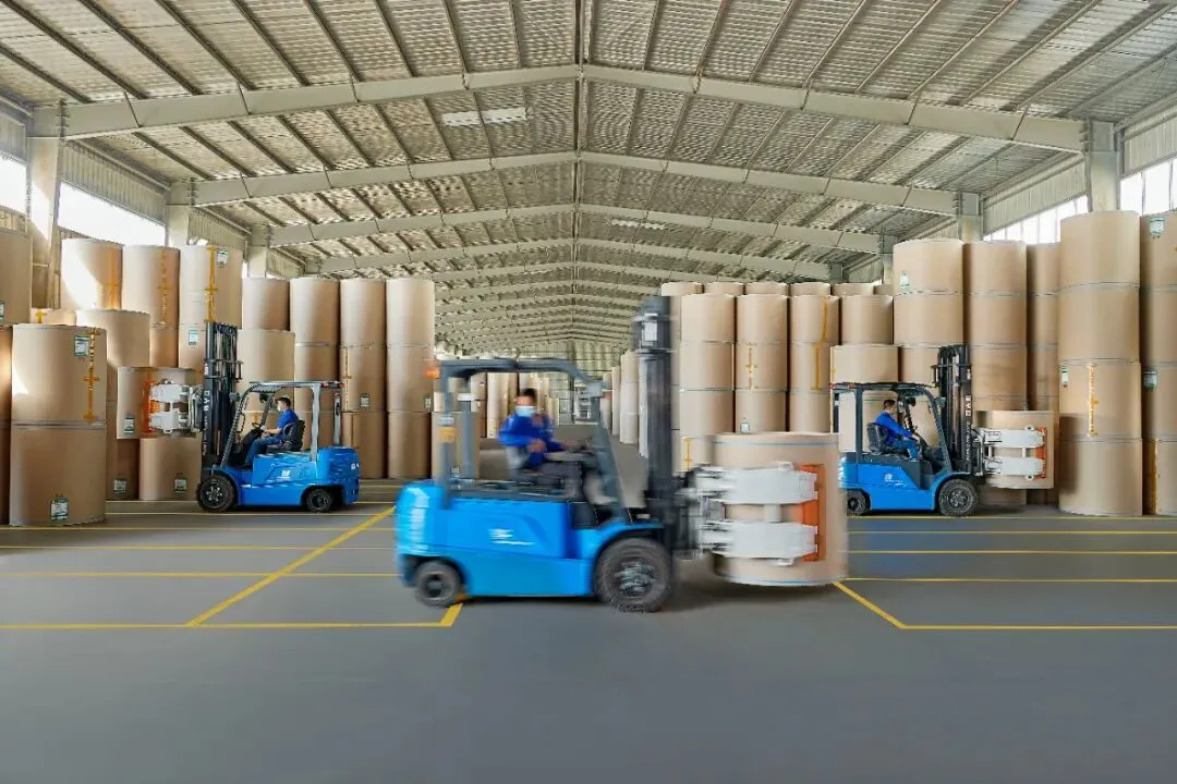 BYD forklifts handling paper rolls with roll clamps inside a warehouse